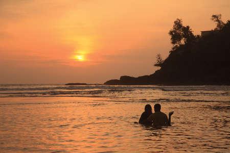 Silhouette of an unidentified couple enjoying in the beach during sunsetの写真素材