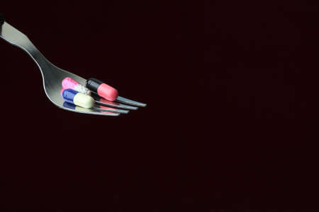 Conceptual shot of capsules on fork in a dark backgroundの写真素材