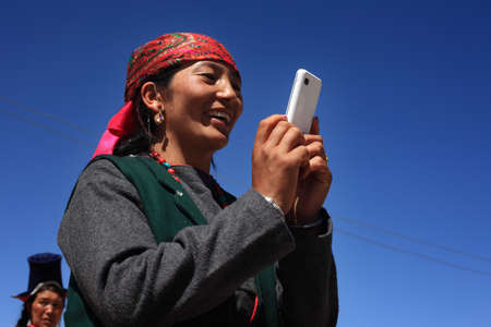 LEH, INDIA - SEPT 01 ,2012- An unidentified Ladakhi woman in her traditional wear takes photo in her mobile phone during a cultural procession during Ladakh Festival  in Leh, India.のeditorial素材