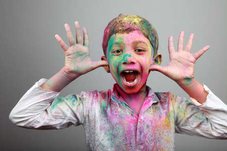 Excited boy with face smeared with colored powder. Concept for festival Holi