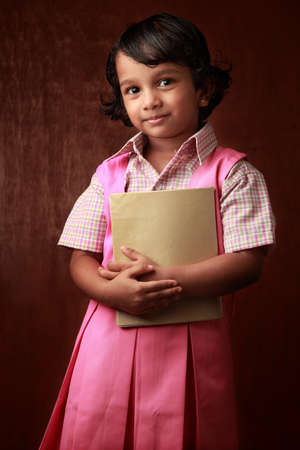 Little girl in school uniform holds a book in hand