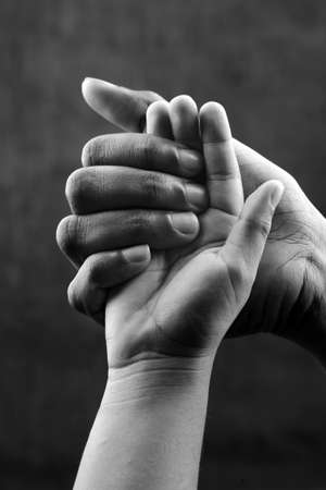Monochrome image of a hand of a mother holding a child's hand. Ideal for concepts of care and love.の写真素材