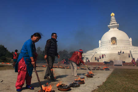 LUMBINI, NEPAL - FEB 08,2014-Buddhist devotees do religious rituals in front of the World peace pagoda  in Lumbini, Nepal.のeditorial素材