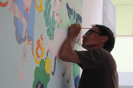 KOTTAYAM, INDIA - MAY 21,2013-Mural artist Tsewang Stanzin paints on the wall during the International Mural painters camp organized by Cultural Department of Kerala in Kottayam, India.のeditorial素材
