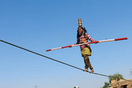 JAISALMER, INDIA - FEB 03, 2015- An unidentified Indian girl performs street acrobatics by walking the rope during the Desert Festival in Jaisalmer, Rajasthan, India.のeditorial素材