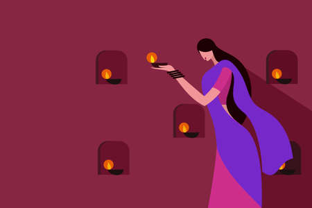 A woman wearing traditional dress lighting Diwali festival lamps