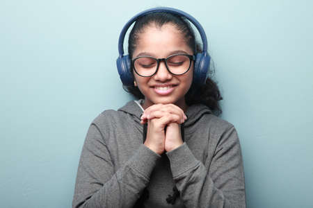 Portrait of a smiling girl of Indian ethnicity listening music with her eyes closedの写真素材