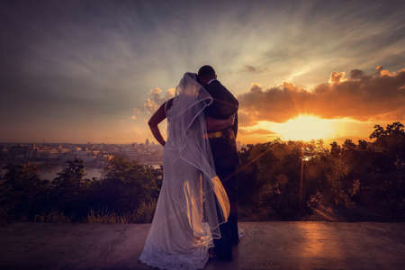 Bride and groom on the background of the city at sunset. Wedding coupleの写真素材
