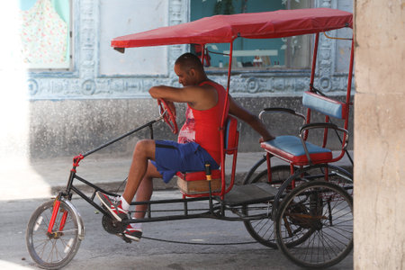 A middle aged Cuban man lies back on his pedicab, waiting for a passenger in  HAVANA, CUBAのeditorial素材