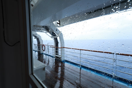 Cruise ship Open deck with Rescue Lifeboats and life buoy through the Window in raindropsの写真素材