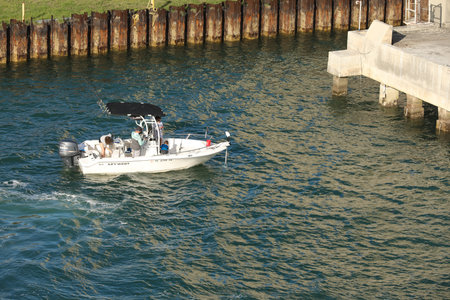 A small center console fishing boat with two fishermen heads out in to the floridaのeditorial素材