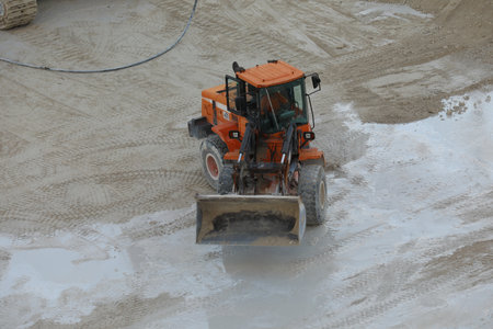 front loader with small wheels against the background of a large pile of stone sand and a blue sky...