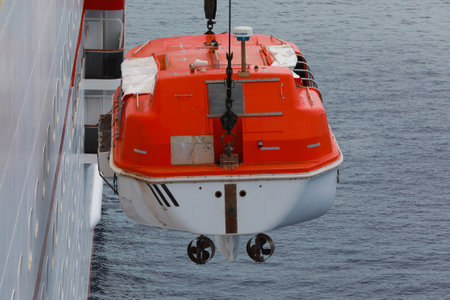Lowering orange totally enclosed lifeboat to water. Abandon ship drill. Lifeboat training. Man over...