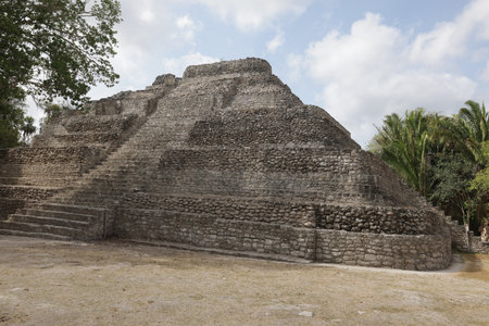 A majestic view of the ruins of the Chacchoben Mayan Ruins with tourists nearbyの写真素材