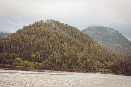 Cruise ship at a port in Juneau, Alaska with snow capped mountain and low lying fog in the backgroundの写真素材