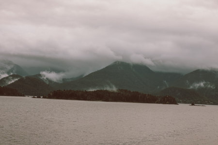 Cruise ship at a port in Juneau, Alaska with snow capped mountain and low lying fog in the...