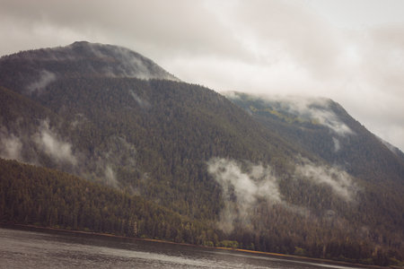 Cruise ship at a port in Juneau, Alaska with snow capped mountain and low lying fog in the backgroundの写真素材