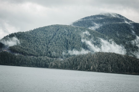 Cruise ship at a port in Juneau, Alaska with snow capped mountain and low lying fog in the backgroundの写真素材