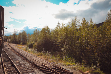 A scenic moment from the White Pass and Yukon Route, showcasing the historic train curving along the mountainous path surrounded by lush evergreens.の写真素材