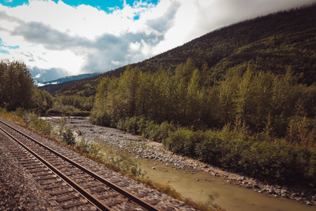 A scenic moment from the White Pass and Yukon Route, showcasing the historic train curving along the mountainous path surrounded by lush evergreens.の写真素材