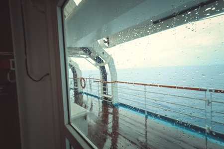 Cruise ship Open deck with Rescue Lifeboats and life buoy through the Window in raindropsの写真素材
