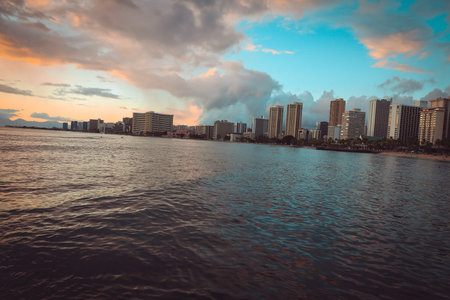 Golden sunset on horizon over Waikiki beach in Oahu, Hawaii, with silhouette of unidentifiable...