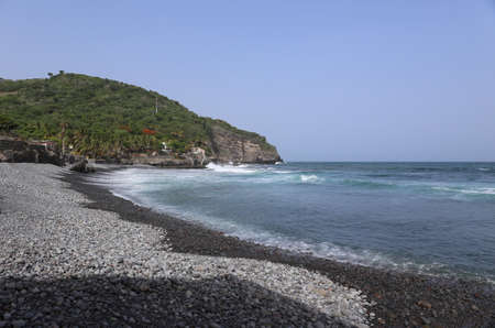 Beautiful turqouise clear sea with black pebble beach at tropical island, Central Americaの写真素材