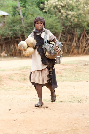 Key Afar, Ethiopia, Febrauary 14, 2013: african woman of the Banna ethnic group with tribal clothes and ornaments is going to the market of the Key Afar village to sell pumpkins,carried with the right hand, used as water or milk storage and butter, carrieのeditorial素材