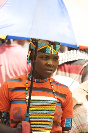 Key Afar, Ethiopia, Febrauary 14, 2013: african men of the Banna ethnic group with tribal decorations are walking at the Key Afar market with an aumbrella for the sun.のeditorial素材