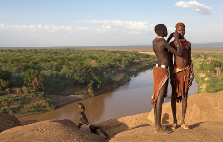 Omo valley, Karo village, Ethiopia, February 16, 2013: african women of the Karo ethnic group show their tribal hairstyle and necklaces with the Omo river in the background. One of them is making the tribal paint on the face of the other.のeditorial素材