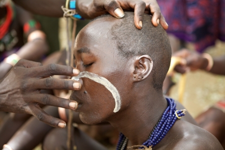 Turmi, Ethiopia, February 16, 2013: african men of the Hamer ethnic group are painting the body to...