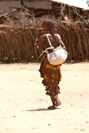 Turmi, Ethiopia, February 17, 2013: african woman of the Hamer ethnic group with tribal hairstyle and clothes are carrying goods at the Turmi marketのeditorial素材