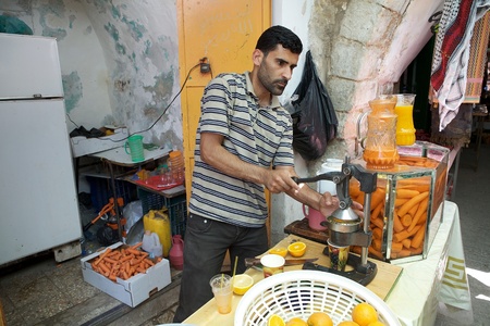 Palestinian man is making the orange juice with fresh oranges in the palestinian sector in Hebron, Israelのeditorial素材