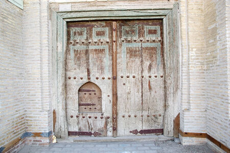 Ancient wooden door in the historic centre of Bukhara, Uzbekistan. Bukhara is a city museum with over 140 architectural monuments. The historic centre of Bukhara, which contains numerous mosques and madrassasのeditorial素材
