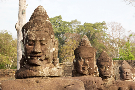 A row of devas faces on le left side of the causeway that spans the moat in front of Angkor Thom South gate, Siem Reap, Cambodia.  Angkor Thom was the last and most enduring capital of Khmer Empire and covers an area of 9 Kmsq within which are located sevの写真素材