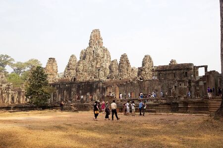 Tourists are visiting the Bayon temple where there are the smiling faces on the face tower, Angkor, Siem Reap, Cambodia. Each tower supports from one to four gigantic smiling faces. Bayon is a richley decorated Khmer temple at Angkor. It was built in lateのeditorial素材