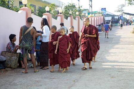 Buddhist monks in their robes are walking along the street near the Kyaiktiyo Pagodaのeditorial素材