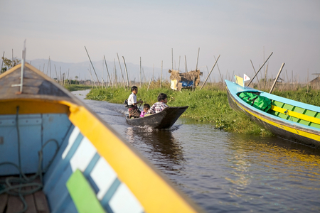 Burmese woman with child is going among the floating gardens by traditional boat on the Lake Inle, Shan State, Myanmar. Traditional agriculture method wich used a small rectangular areas of fertile land to grow crops on the shallow lake bedのeditorial素材