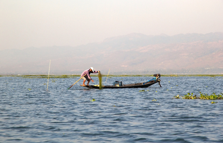 Burmese fisherman is fishing by traditiona boat on the lake Inle, Shan State, Myanmar.のeditorial素材