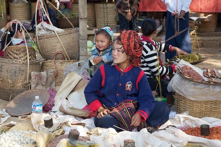 Burmese vendor with child is selling food at the Nan Pan village market on the Lake Inle, Shan State, Myanmarのeditorial素材