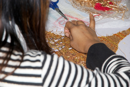Burmese woman is making a burmese traitional tapestry and she is using a golden threads for...
