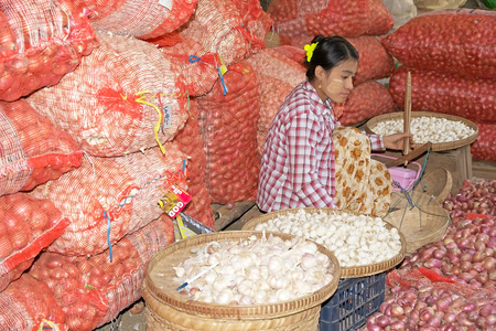 Burmese woman in traditional clothes is selling onions at the Nyang U market, Bagan, Myanmar. Located in the northeastern part of Bagan, Nyaung U market is Nyaung village's local market, where it is possible find goods in different section.のeditorial素材