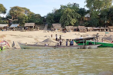 Burmese workers are carrying sand from the boats to the Irrawaddy river bank in Bagan, Myanmar. Irrawaddy river flows from North to South in Myanmar. It is the Country largest river and most important commercial waterway.のeditorial素材