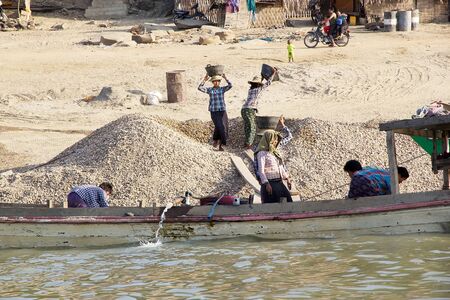 Burmese workers are carrying sand from the boats to the Irrawaddy river bank in Bagan, Myanmar. Irrawaddy river flows from North to South in Myanmar. It is the Country largest river and most important commercial waterway.のeditorial素材