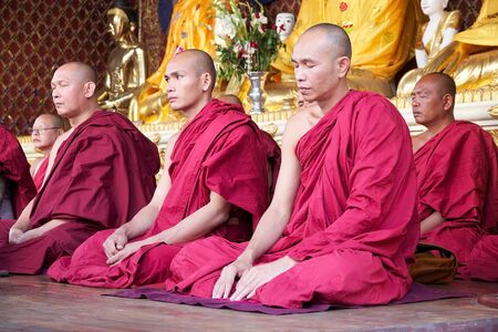 Buddhist monks in traditional robes in meditation at the Shwedagon Pagoda, a gilded stupa located in Yangon, Myanmar. The pagoda is the most sacred Buddhist pagoda in Myanmar.のeditorial素材
