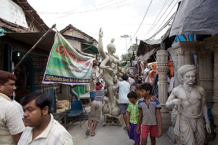 Traditional potters are carrying and pushing a clay idol of Hindu Gods along the street in Kumortuli, the traditional potters' quarter in northern Kolkata, West Bengal, India. This Kolkata neighbourhood not only supplies clay idols of Hindu Gods in Kolkatのeditorial素材