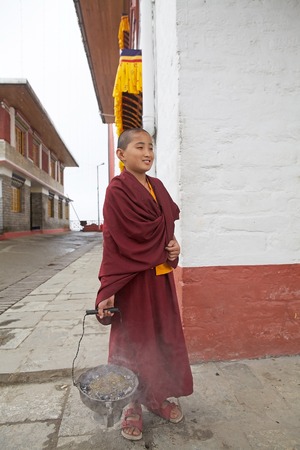 Young Buddhist monk in traditional robes is carrying the fire for a ceremony at the Pemayangtse Monastery, Sikkim, India. Pemayangtse Monastery is a Buddhist monastery in Pemayangtse, near Pelling, Indian State of Sikkim. Founded by Lama Lhatsun Chempo inのeditorial素材