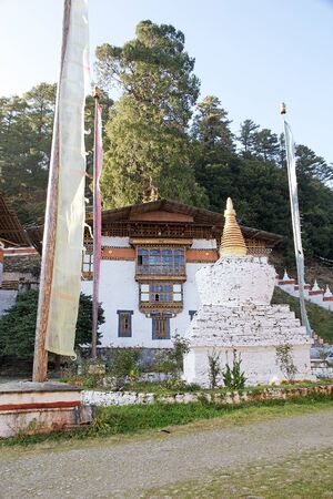 Chorten and prayer flag at the Kurjey Lhakhang also known as Kurjey Monastery, located in the Bumthang Valley in the Bumthang District, Bhutan. This is the final resting place of the first three King of Bhutan. Also, a large tree behind one of the temple の写真素材