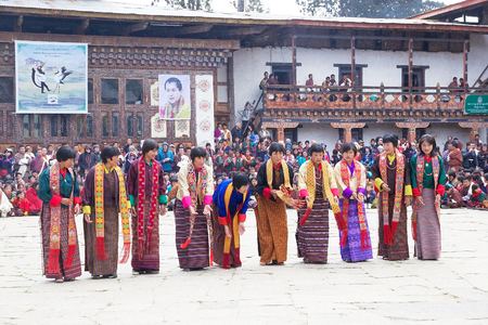 Dancers,women from the local community, with traditional clothes and masked clown, Atsaras, are performing the Zhungdra dance during the Black-necked crane Festival at the Gangtey Monastery also known as Gantey Gompa, Gangten, Bhutan. The masked clown is のeditorial素材