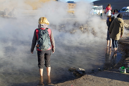 Tourists are, with the feet, in the hot water natural pool at the El Tatio geysers, Chile. El Tatio is a geyser field located in the northern Chile. It is the largest geyser field in the southern hemisphere and the third geyser field in the world.のeditorial素材